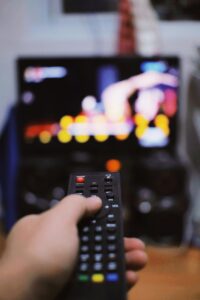 person watching tv and holding a remote control